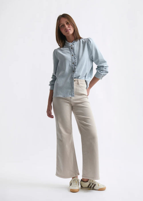 Woman wearing a light blue shirt and beige pants on a white background