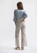 Woman wearing a light blue shirt and beige pants on a white background