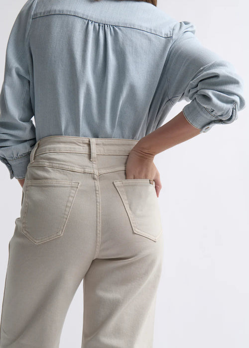 Woman wearing a light blue shirt and beige pants on a white background