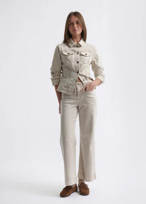 Woman wearing a beige denim jacket and pants on a white background