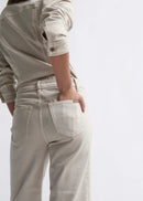 Person wearing a beige jacket and pants on a white background