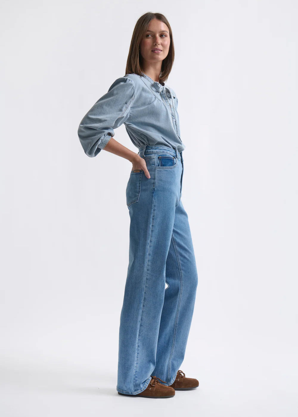 Woman wearing a denim shirt and jeans on a white background