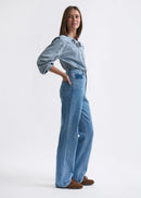 Woman wearing a denim shirt and jeans on a white background
