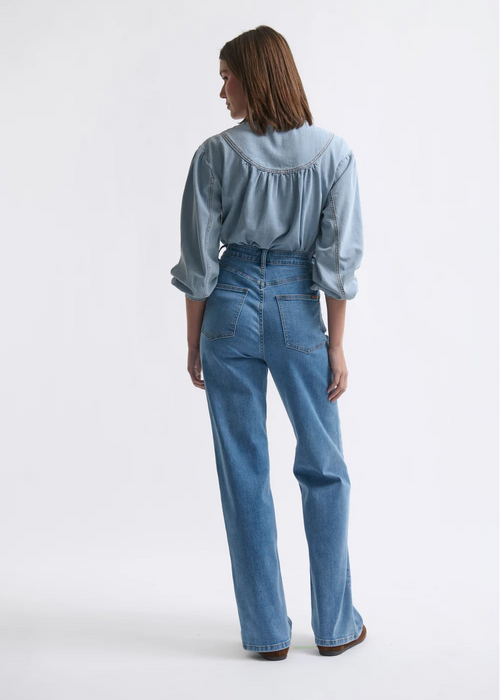 Person wearing a light blue denim shirt and jeans on a white background