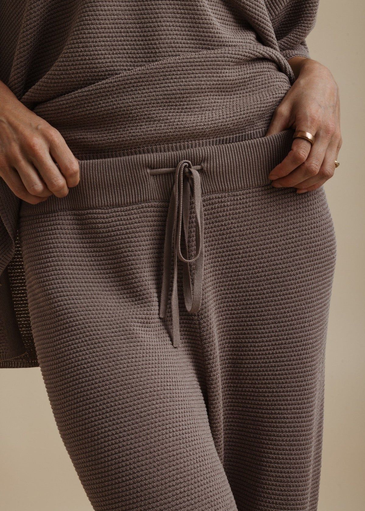 Woman modelling brown tie pants on beige background