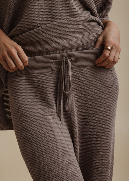 Woman modelling brown tie pants on beige background