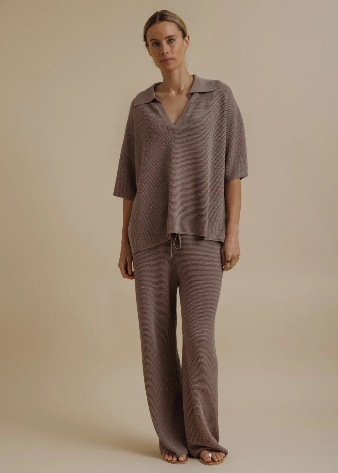 Woman modelling brown tie pants on beige background