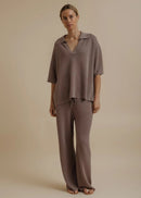 Woman modelling brown tie pants on beige background