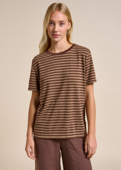 Woman wearing a brown striped shirt against a beige background