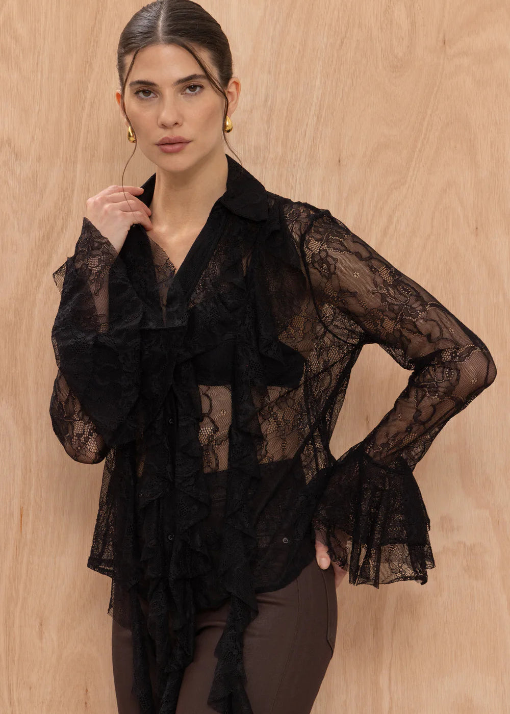 Woman wearing a black lace top against a beige background