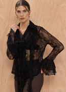 Woman wearing a black lace top against a beige background