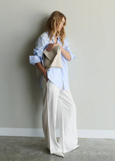 Woman holding a beige tote bag against a plain wall