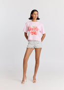Woman wearing a pink 'Sweetie' t-shirt and patterned shorts on a white background