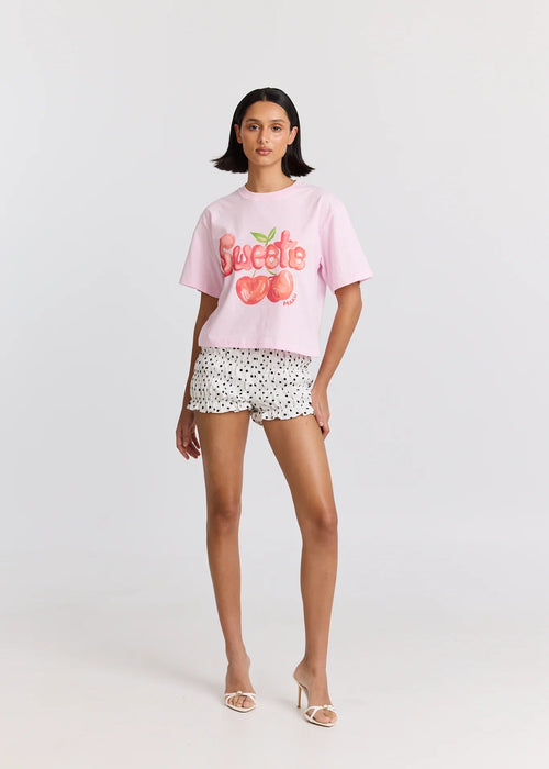 Woman wearing a pink 'Sweetie' t-shirt and patterned shorts on a white background