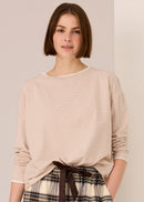 Woman wearing a white beige top against a plain background