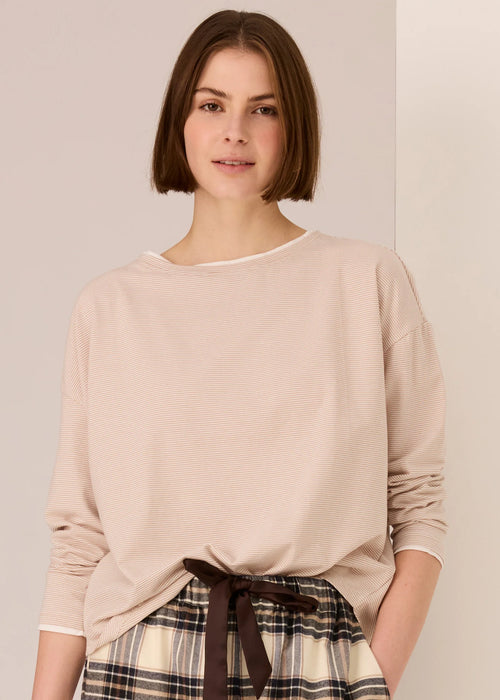 Woman wearing a white beige top against a plain background