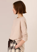 Woman wearing a white beige top against a plain background