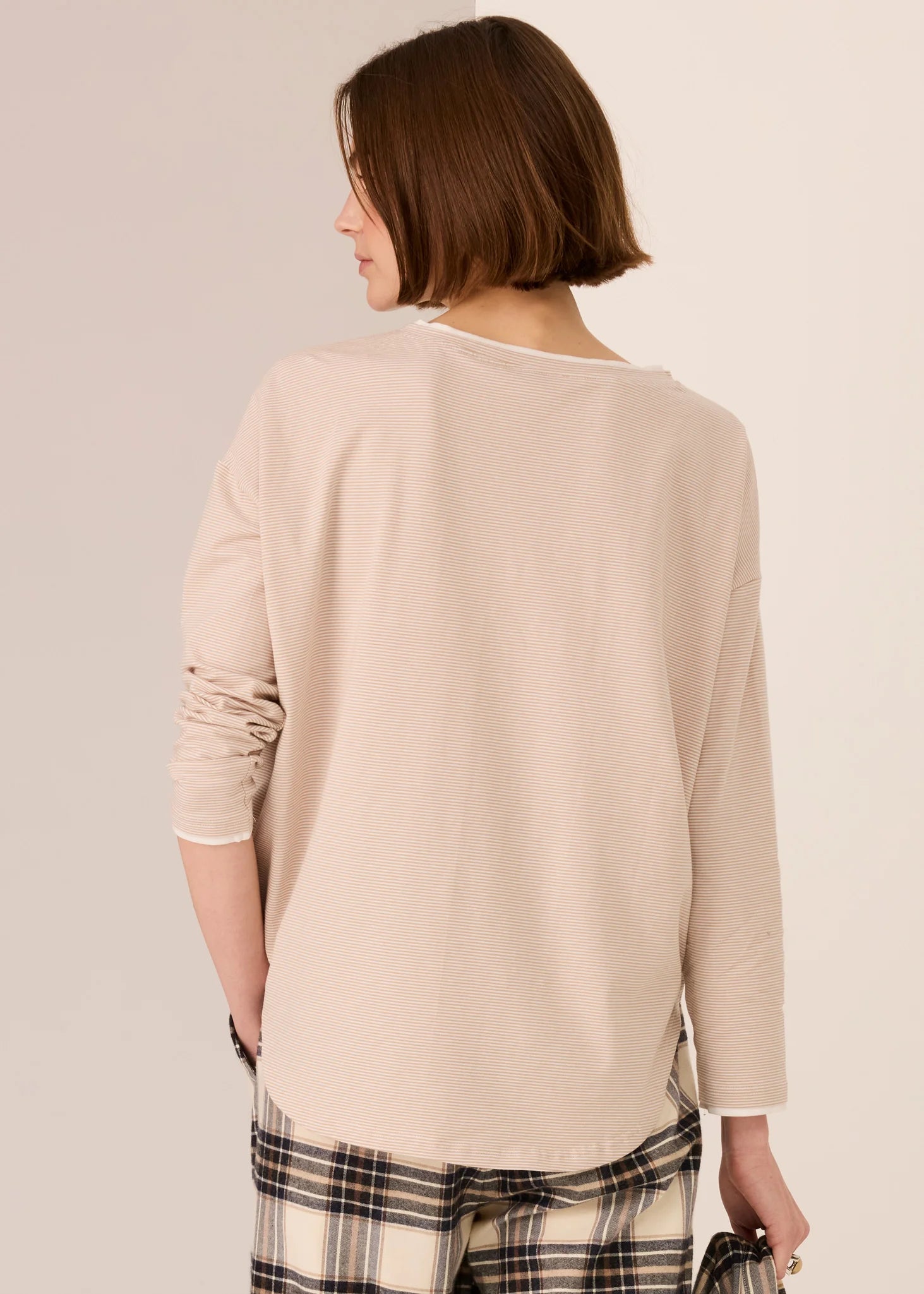 Woman wearing a white beige top against a plain background