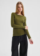 Woman wearing a green long-sleeve top and black pants on a light gray background