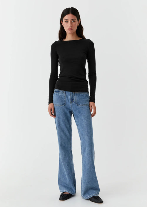 Woman wearing a black long-sleeve top and blue jeans on a white background