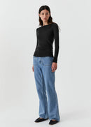 Woman wearing a black top and blue jeans on a white background
