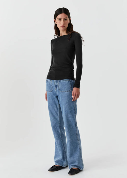 Woman wearing a black top and blue jeans on a white background
