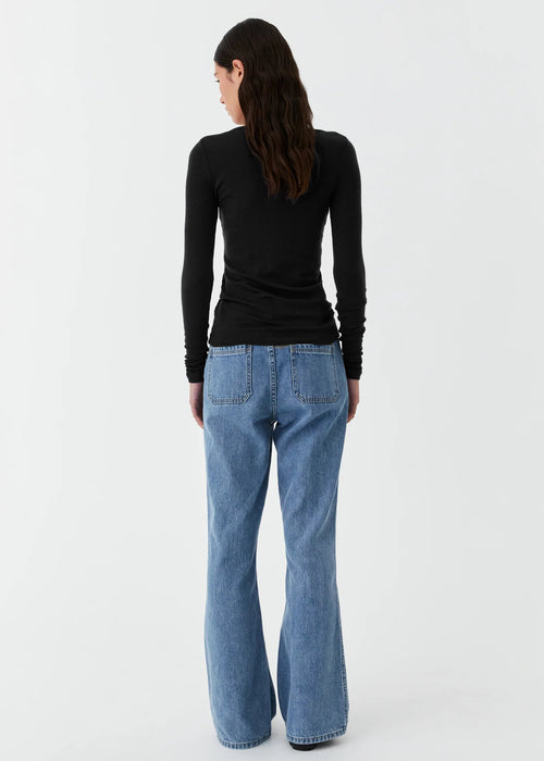 Person wearing blue jeans and a black long-sleeve shirt on a white background