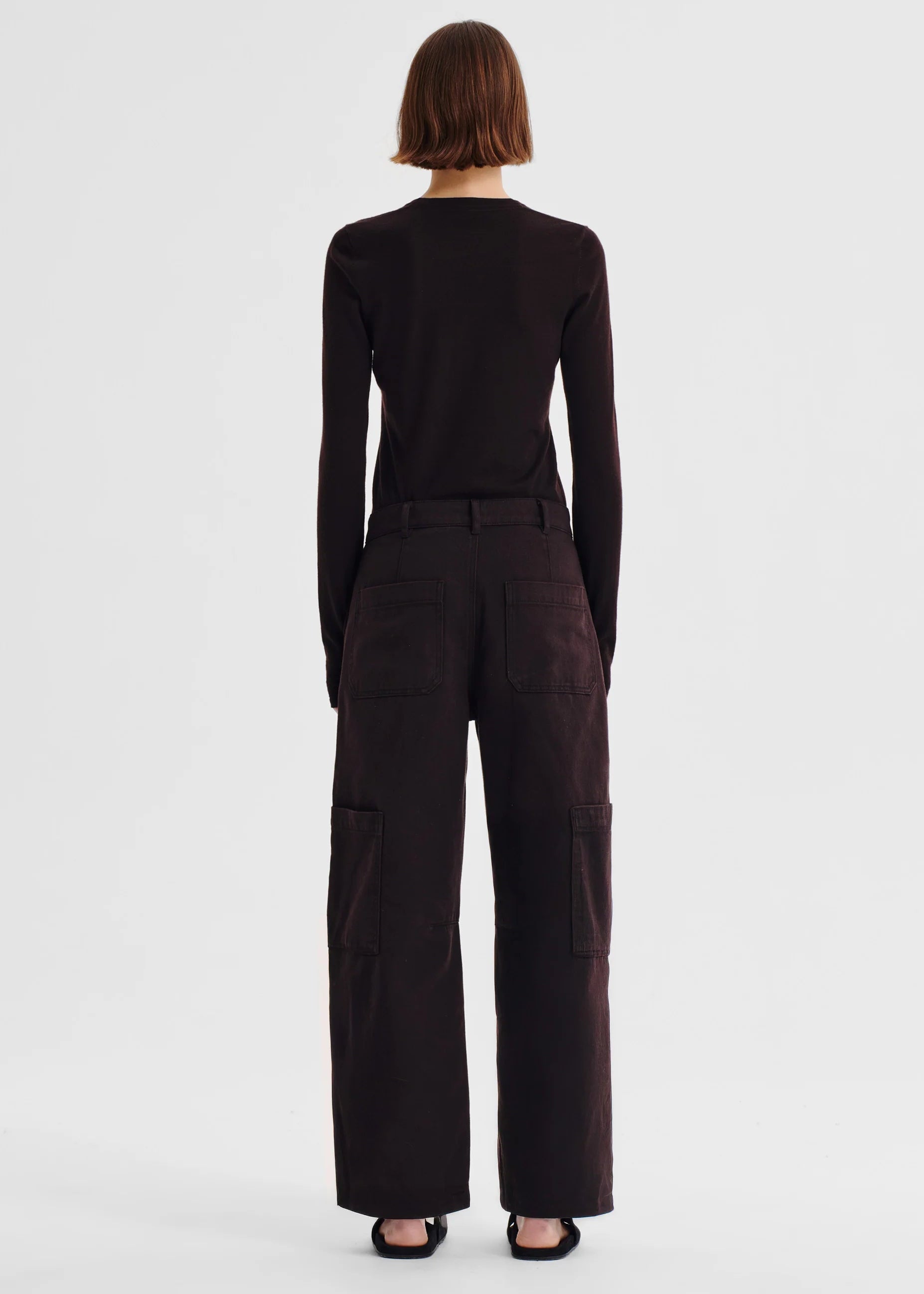Person wearing a dark brown outfit on a white background