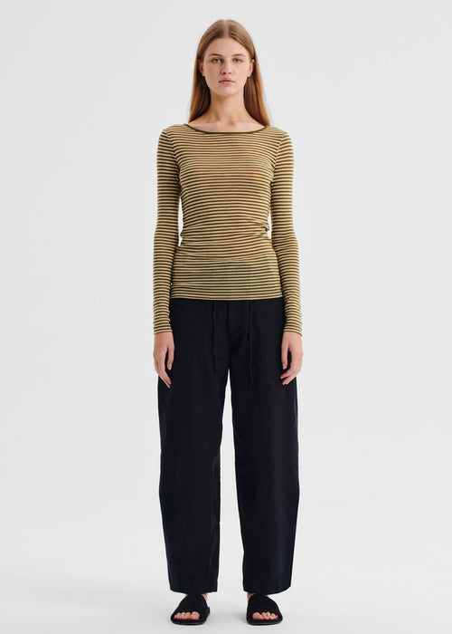 Woman wearing a striped long-sleeve top and black pants on a white background