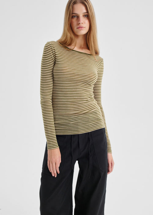 Woman wearing a striped long-sleeve top and black pants on a light gray background