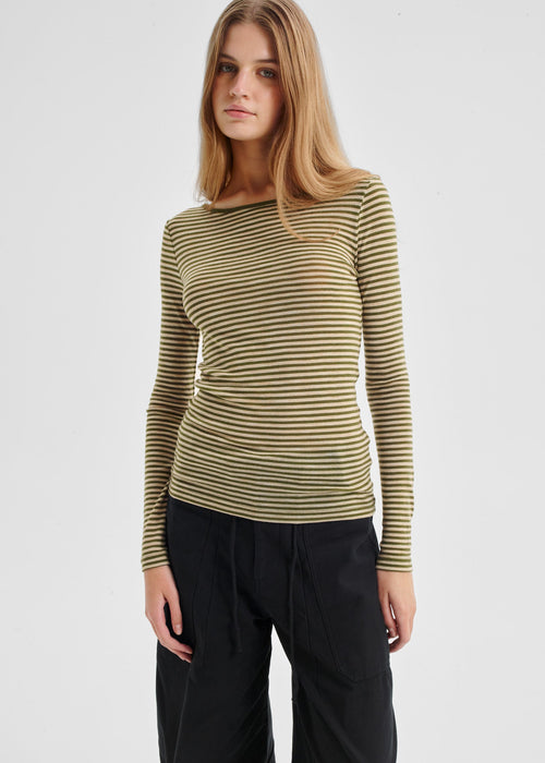 Woman wearing a striped long-sleeve top and black pants on a light gray background