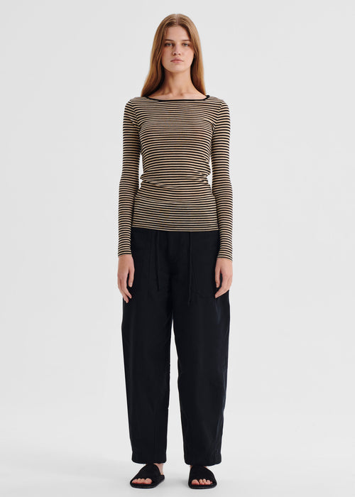 Woman wearing a striped long-sleeve top and black pants on a white background