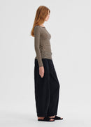 Woman wearing a striped long-sleeve top and black wide-leg pants on a white background