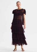 Woman wearing a dark brown dress with layered skirt on a white background