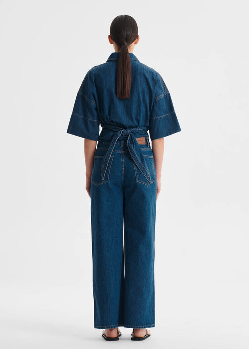 Person wearing a blue denim top on a white background