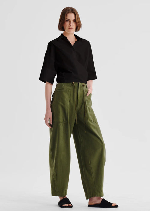 Woman wearing a black shirt and green pants on a white background