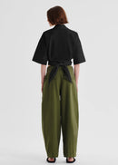 Person wearing a black shirt and green pants on a white background