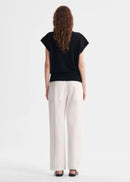 Person wearing a black top and white pants on a white background