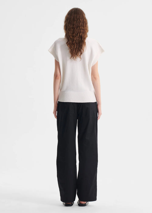 Woman wearing a white top and black pants on a white background