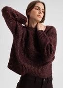 Woman wearing a maroon sweater against a plain background