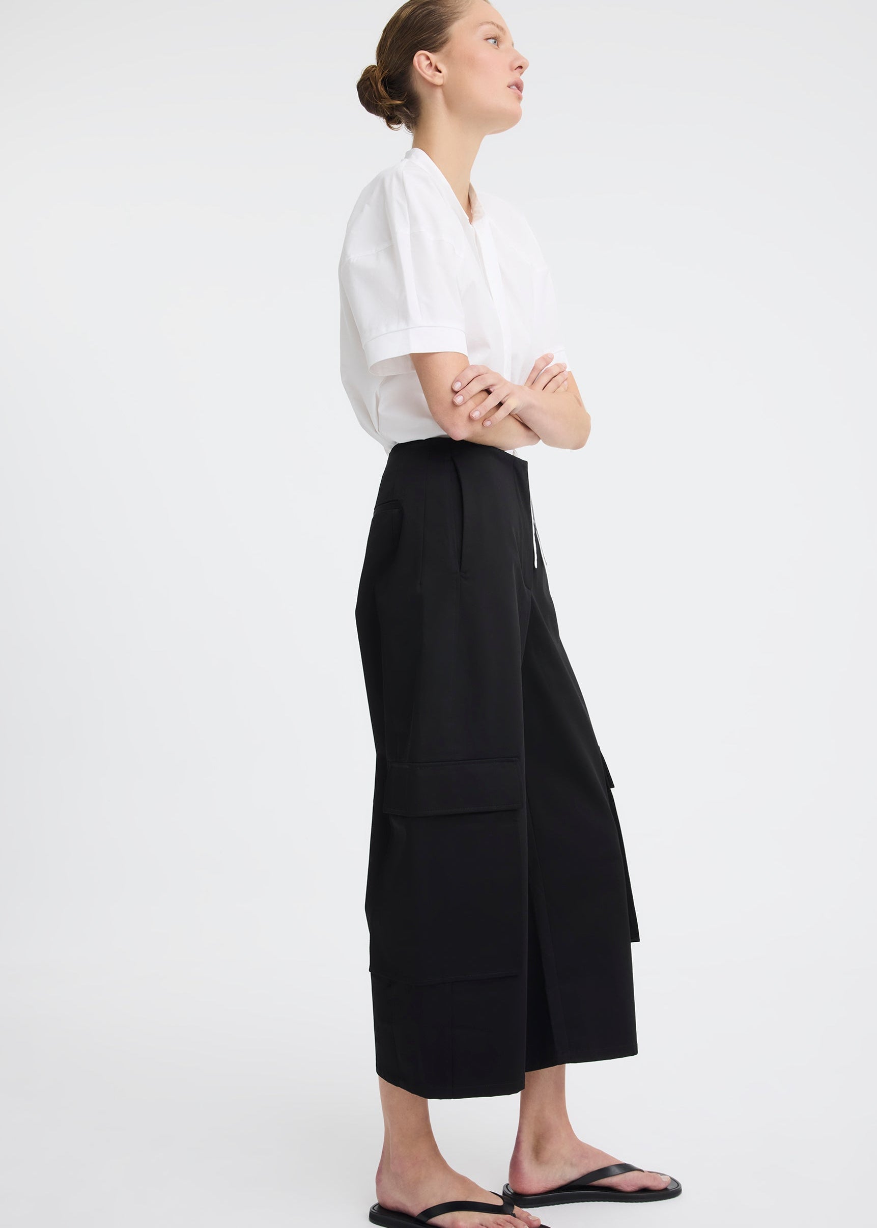 Woman wearing black pants and white top on white background