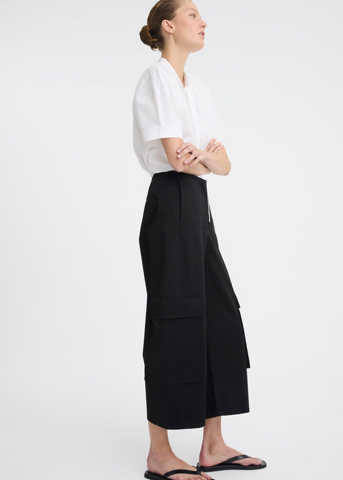 Woman wearing black pants and white top on white background