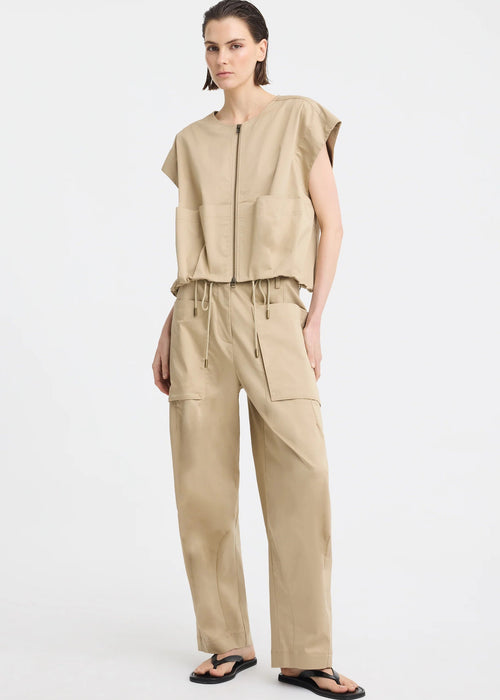 A model wearing a beige sleeveless top and matching wide-leg cargo pants, paired with black flip-flop sandals, photographed against a plain white studio background.