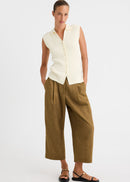 A model wearing a sleeveless cream button-front knit vest and olive-brown cropped wide-leg trousers, paired with black flat sandals, against a plain light gray studio background.