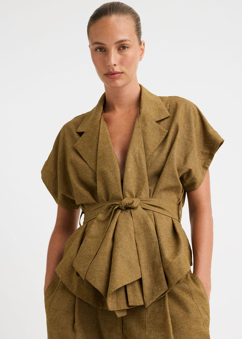 A model wearing a matching olive-brown linen two-piece set featuring a belted wrap-style top and wide-leg trousers, shot against a plain light grey studio background.
