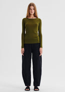 Woman wearing a green long-sleeve top and black pants on a white background

Details