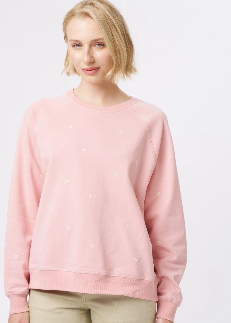 A woman modelling a light pink long-sleeve crewneck sweatshirt and beige wide-leg cropped pants, paired with patterned flat shoes, against a plain white studio background.
