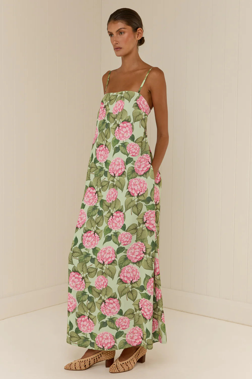 Woman wearing a floral dress with pink flowers on a plain background