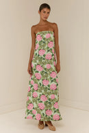 Woman wearing a strapless floral dress with pink flowers on a plain background