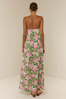 Woman wearing a strapless floral dress with pink flowers on a plain background
